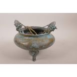 A Chinese bronze censer on tripod supports with two dragon handles and applied verdigris patina,