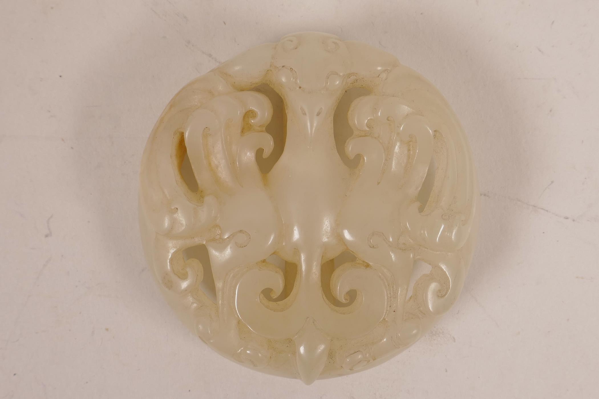 A Chinese white jade belt buckle with carved and pierced phoenix decoration, 2" diameter