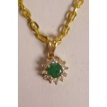 A 14ct yellow gold pendant set with an emerald encircled by diamonds, on a gilt chain