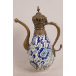 An Iznik pottery ewer decorated with scrolling flowers, with metal spout, handle and lid, 12" high