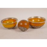 Two faux amber bowls with white metal mounts with repousse decoration, largest 4½" diameter,