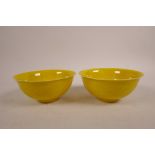 A pair of Chinese yellow ground porcelain rice bowls with incised decoration of a dragon chasing the