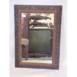 A late C19th composition framed mirror, with raised swag and floral decoration, 22" x 30½"