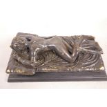 A bronze figurine of a nude female lying on a bed, 9" long