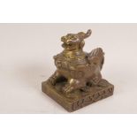 A Sino-Tibetan bronze figurine of a winged kylin seated upon a pile of auspicious coins, signed with