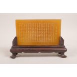 A Chinese amber soapstone tablet on a hardwood stand with engraved character inscription, 7½" wide x