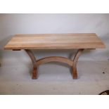 A bespoke limed oak dining table, with two end leaves and plank top, raised on a shaped base,