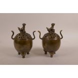A pair of Chinese bronze censers on tripod supports with two handles, pierced covers and a knop in