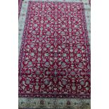A red ground Kashmiri rug with all over floral design and gold border, 61" x 90"