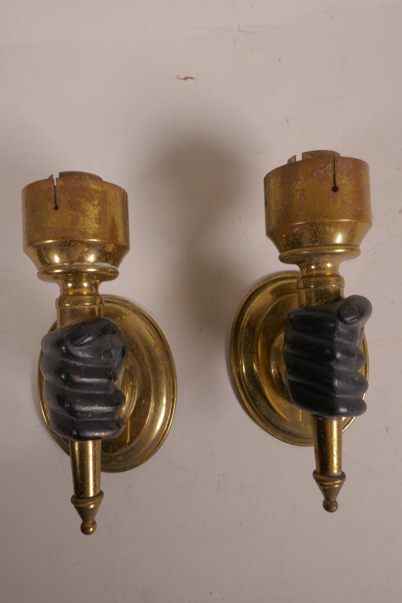 A pair of brass wall lights, with bronze hands clasping the torcheres, 6" high x 3"