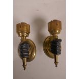 A pair of brass wall lights, with bronze hands clasping the torcheres, 6" high x 3"