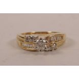 A 9ct gold and diamond ring, with a central round brilliant cut diamond flanked by baguette