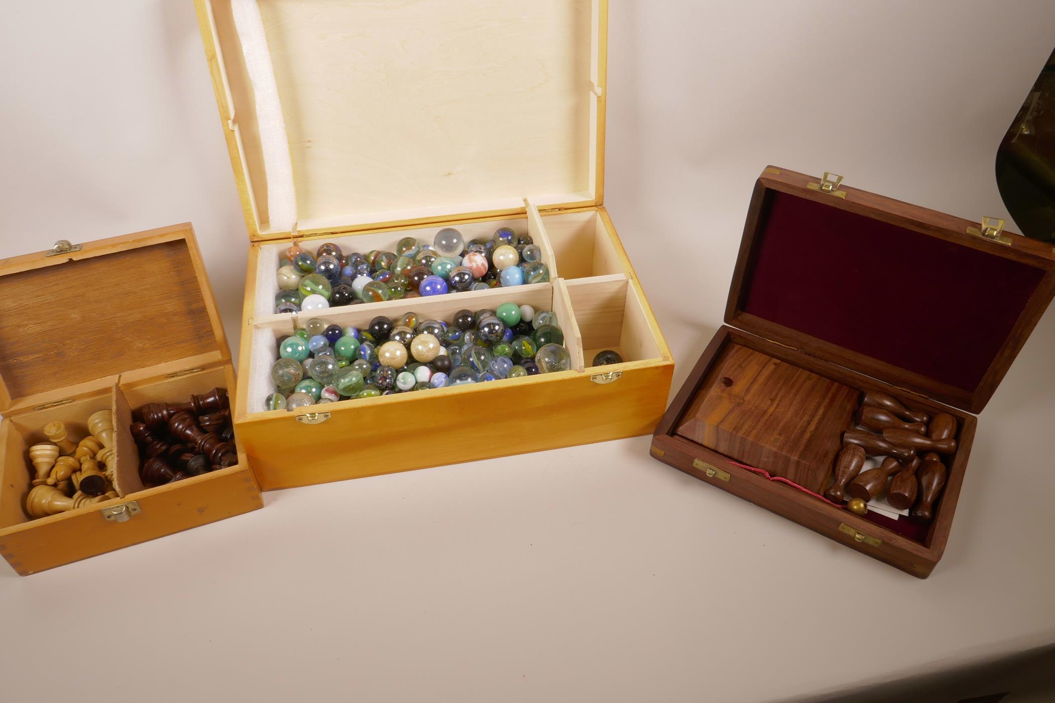 A box of vintage glass marbles together with a set of matched chess pieces and a table skittles game