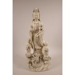 A Chinese blanc de chine figure of Quan Yin with two children and a dragon, impressed mark verso,
