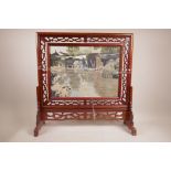 An Oriental mahogany table screen with pierced frame and swivel panel with silkwork landscape