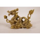 A Chinese gilt metal figure of a dragon clutching the flaming pearl, 8" long