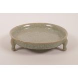 A Chinese celadon crackleware shallow dish raised on tripod supports, 5½" diameter