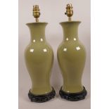 A pair of Chinese porcelain baluster vase table lamps with terre verte glaze on carved wood bases,