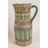 A Morrocan earthenware jug with white metal wirework decoration, painted in earth colours, 9" high