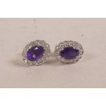 A pair of 18ct white gold, amethyst and diamond cluster earrings, approximately 90 points