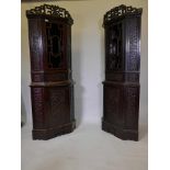A pair of Chinese two section lacquered corner cabinets, with open and blind fret decoration, and
