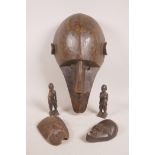 An early African carved hardwood tribal mask, 15" long, possibly Dogon, together with two smaller