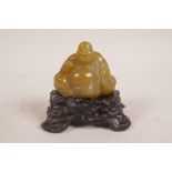 A Chinese carved soapstone Buddha, mounted on a carved hardwood stand, 4" high