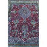 A Middle Eastern hand woven wool Qum carpet with vase and flower designs on a red field with gold