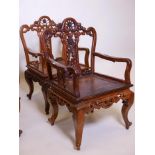 A pair of Chinese hardwood open armchairs with carved and pierced backs and friezes, raised on