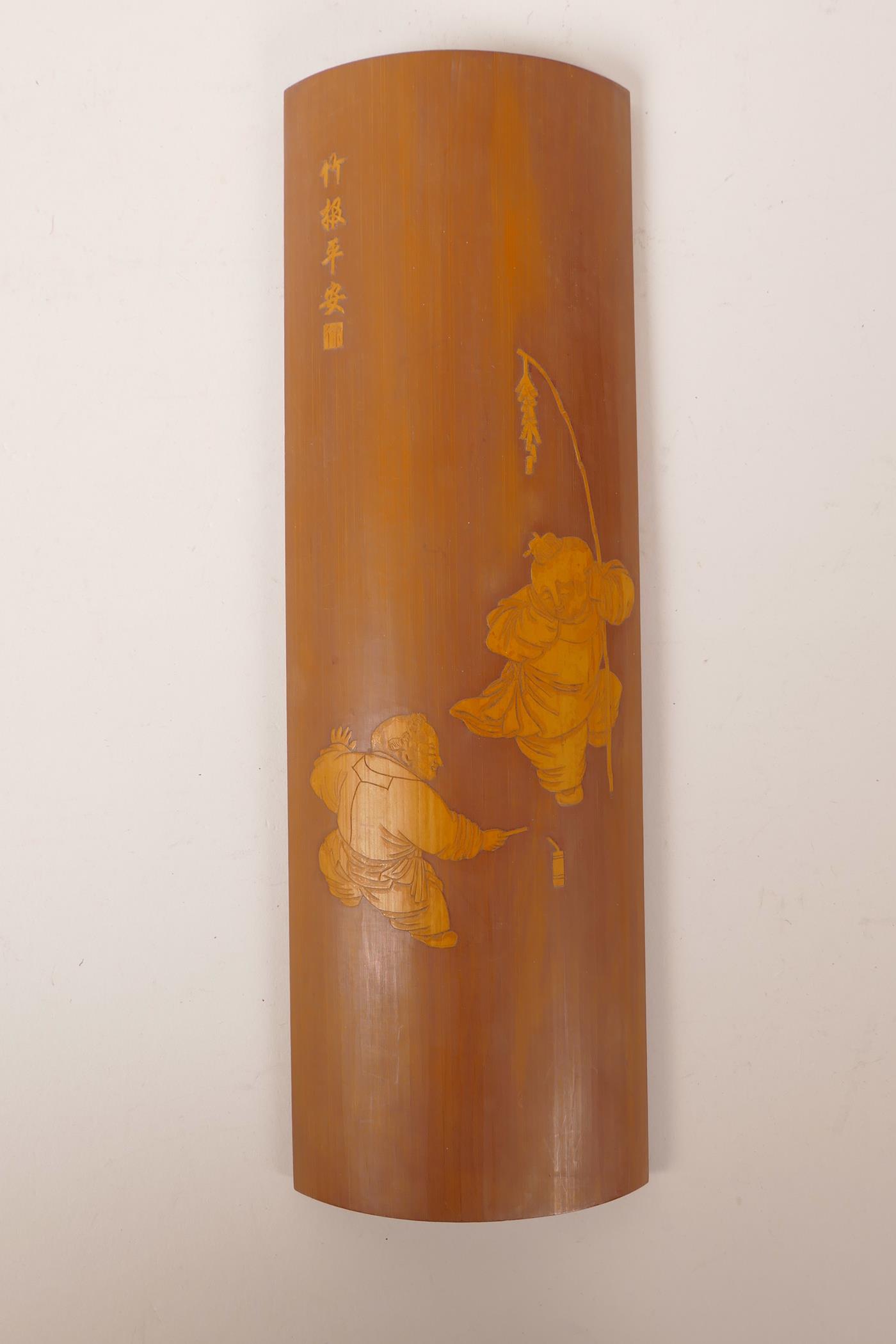 A Chinese carved bamboo wrist rest decorated with boys playing with fireworks, 12" long