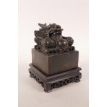 A Chinese filled metal square form seal with dragon decoration, on a hardwood stand, 4½" x 4½"