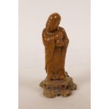 A Chinese amber soapstone carving of Lohan, standing on a carved soapstone base, 5" high, A/F repair