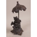 A bronze figurine of a bear seated on a rock and holding a parasol, 8" high