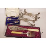 A cased pair of silver plated fish servers with pierced and engraved decoration, together with a