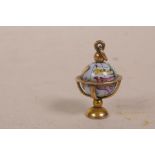 A 9ct gold charm with revolving porcelain globe, 2.6 grams total