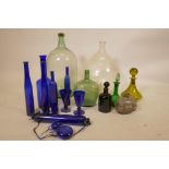 A collection of blue glass bottles, coloured glass decanters, a white metal mounted glass bottle,
