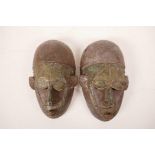 A pair of African carved wood masks with applied, hammered metal decoration, 5½" x 9½"