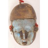 An African carved wood tribal mask with unusual metal overmask and shell earrings, 9" long