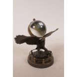 A desk clock in the form of an eagle bearing a glass ball, 7" wide