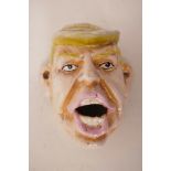 A cast iron wall mounted bottle opener modelled as Donald Trump, 4" long
