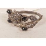 A Chinese silver bangle in the form of a dragon, inset with black beads, probably early C20th, 2½"