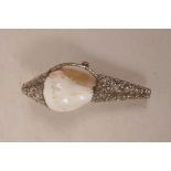 A Tibetan white metal mounted conch shell with raised scrolling floral decoration, set with two