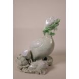 A Chinese tri-colour jade carving of a goose eating foliage amongst rocks and lotus flowers, with