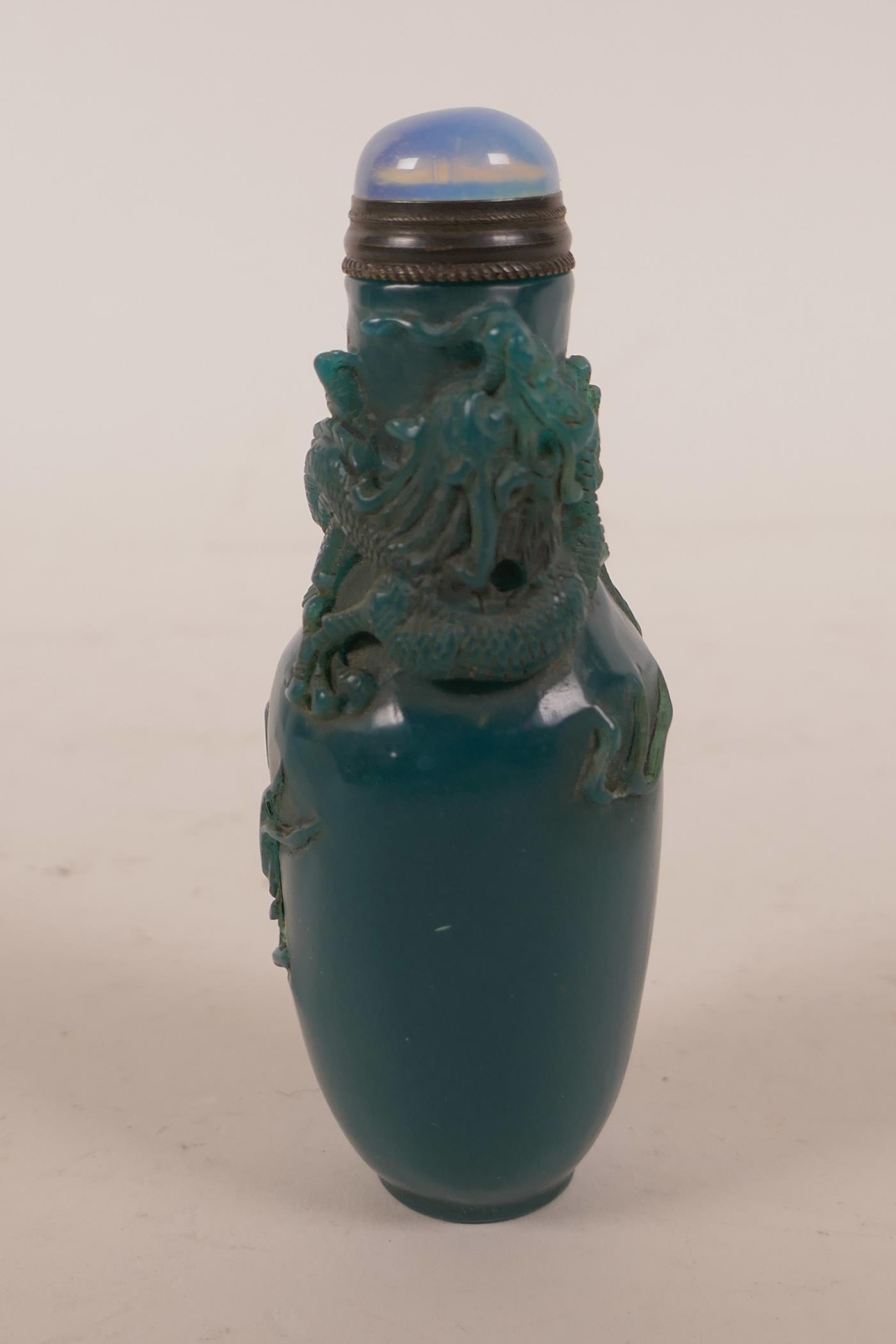 A Chinese blue glass snuff bottle with carved decoration of a dragon chasing the flaming pearl, 4"