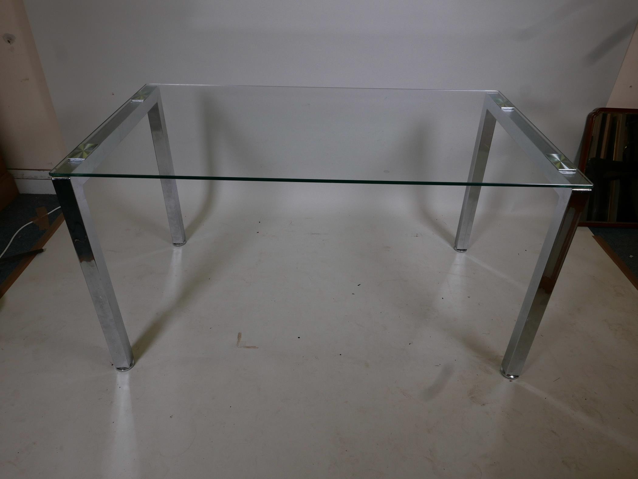 A contemporary glass topped office table on chrome supports, 55" x 31½", 29½" high