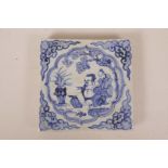 A Chinese blue and white pottery tile decorated with two figures in a landscape, 8" x 8"