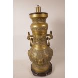 An Oriental bronzed metal table lamp cast with scrolls and masks, mounted on a turned wood base, 20"