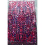 A Persian hand knotted wool rug with geometric designs on a blue field, 67" x 40"