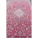 A Persian hand woven wool carpet with all over scrolling floral designs and central medallion, A/F