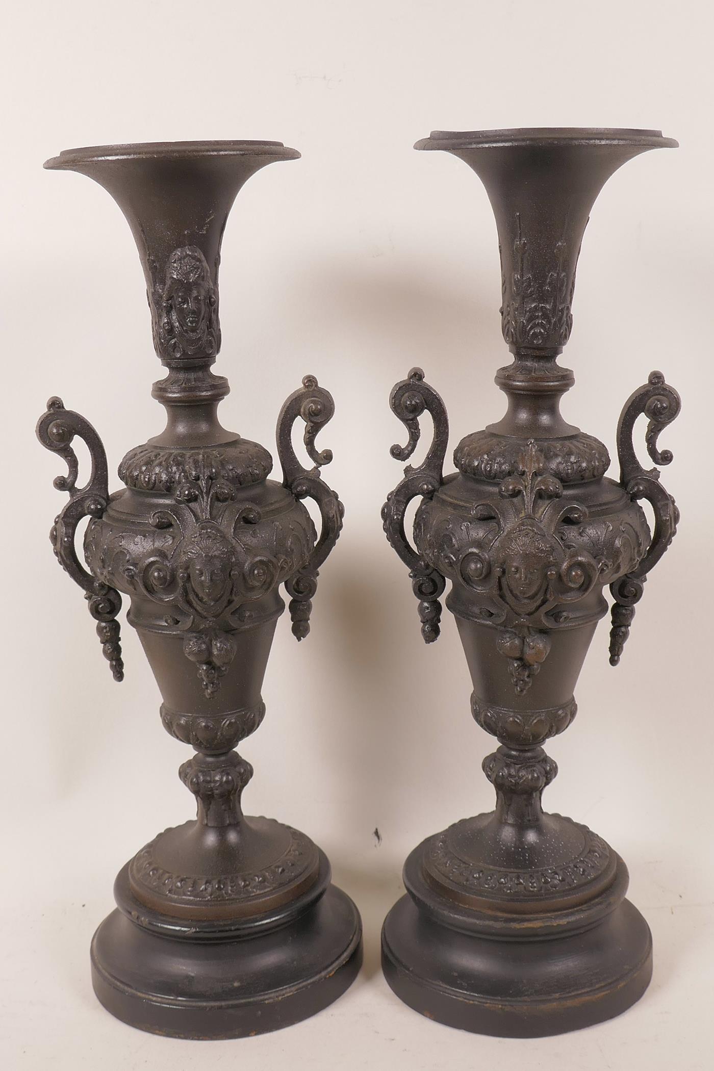 A pair of Victorian spelter side urns decorated with masks and swags, mounted on turned wooden